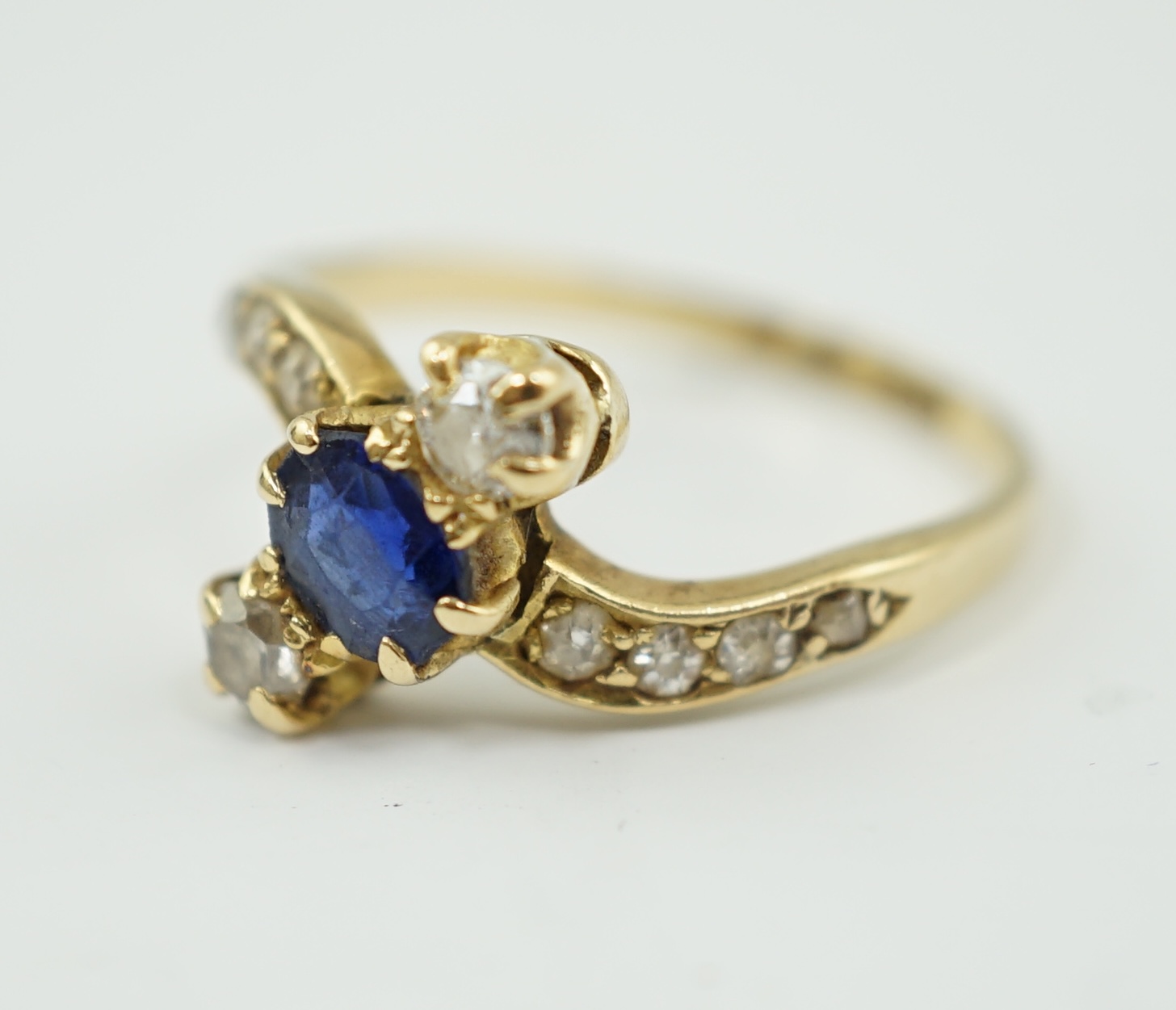 An 18ct gold, sapphire and diamond set three stone crossover ring, with eight stone graduated diamond set shoulders